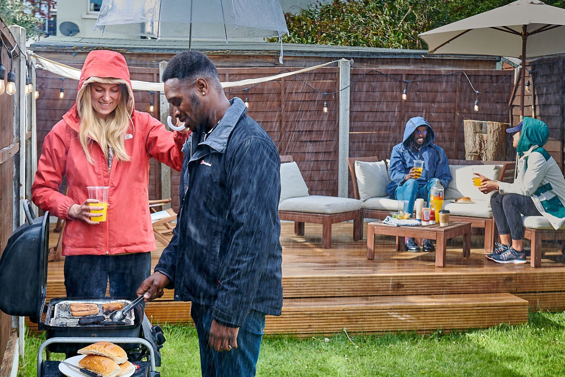 A man and a woman are standing next to a grill in a backyard.