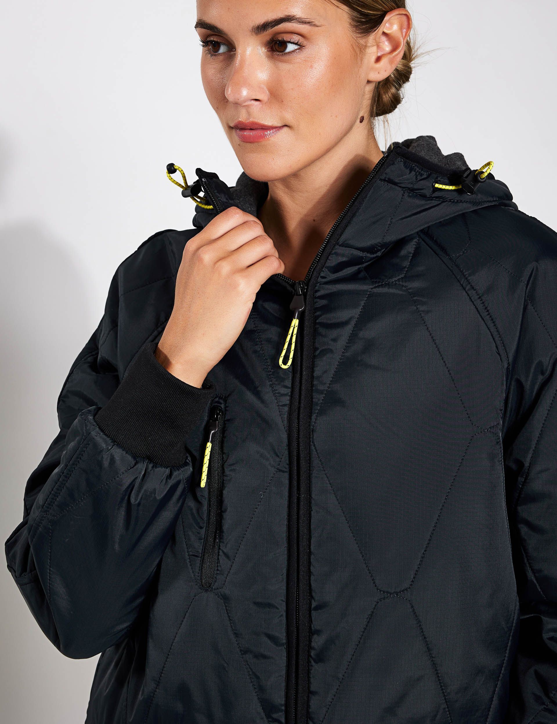 A woman is wearing a black jacket with a hood.