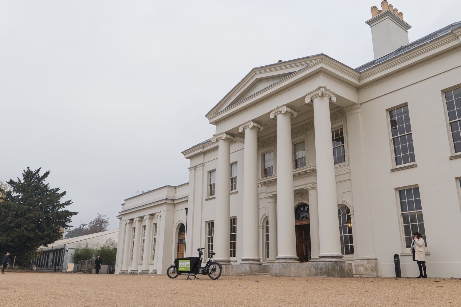 a bicycle is parked in front of a large white building .