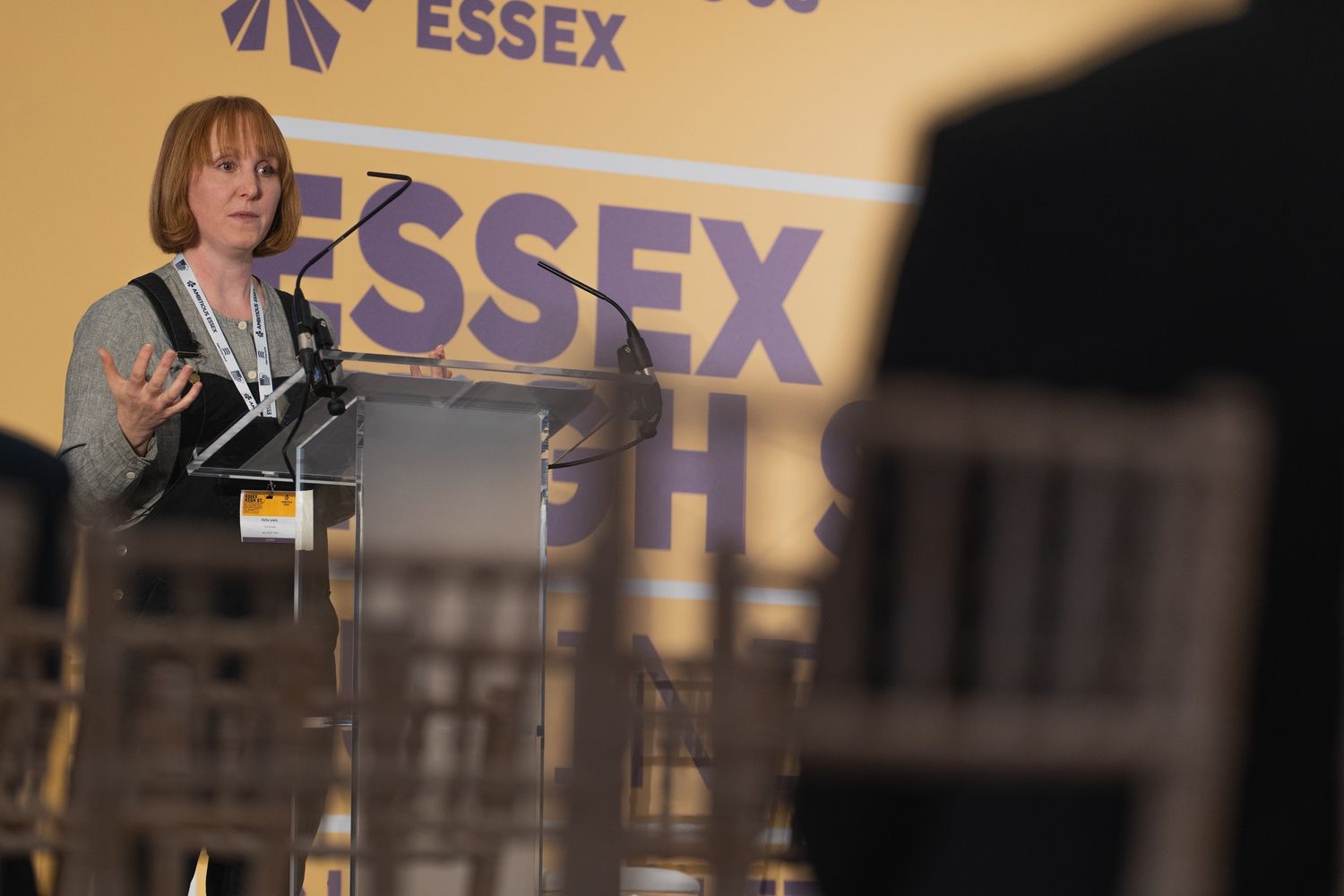 a woman is giving a speech at a podium in front of a sign that says essex