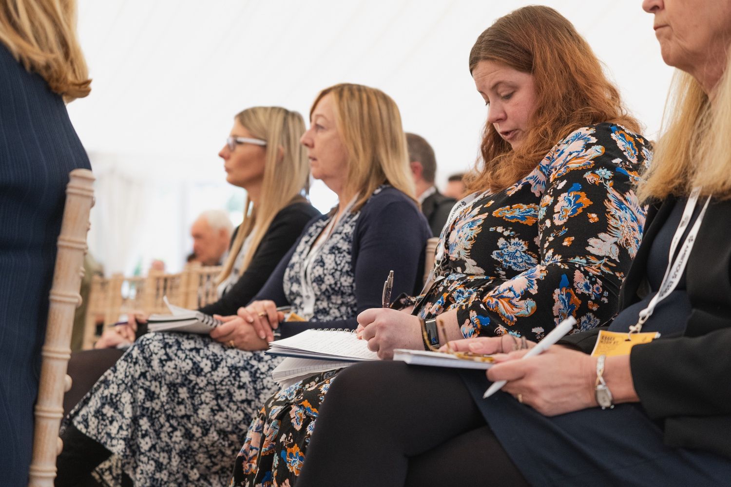 a group of women are sitting in chairs at a conference .
