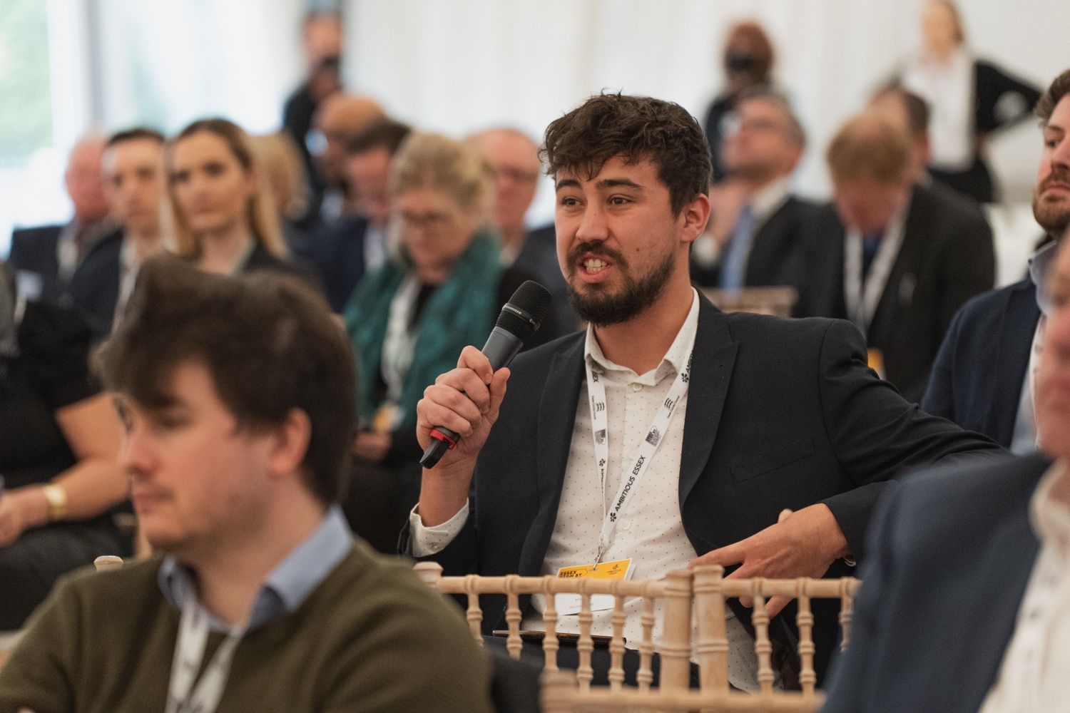 a man is holding a microphone in front of a crowd of people .