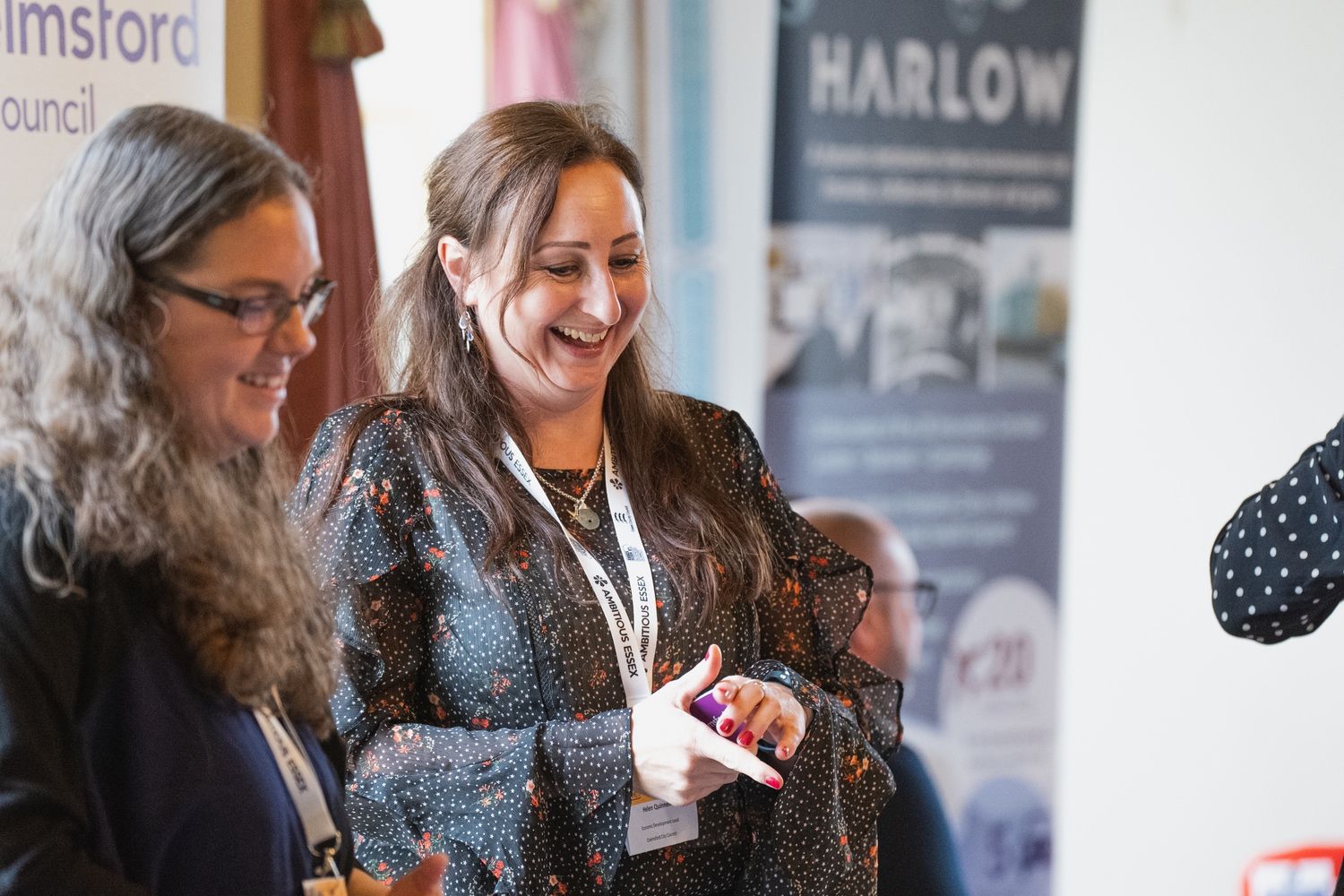 Two women are standing next to each other in front of a sign that says harlow.