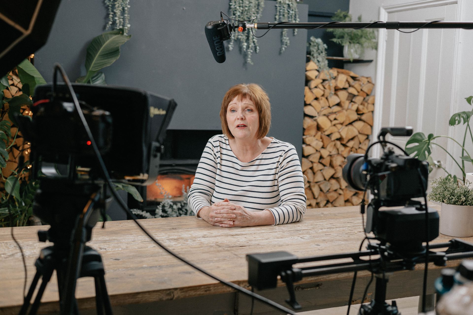 A woman is sitting at a table in front of a camera.