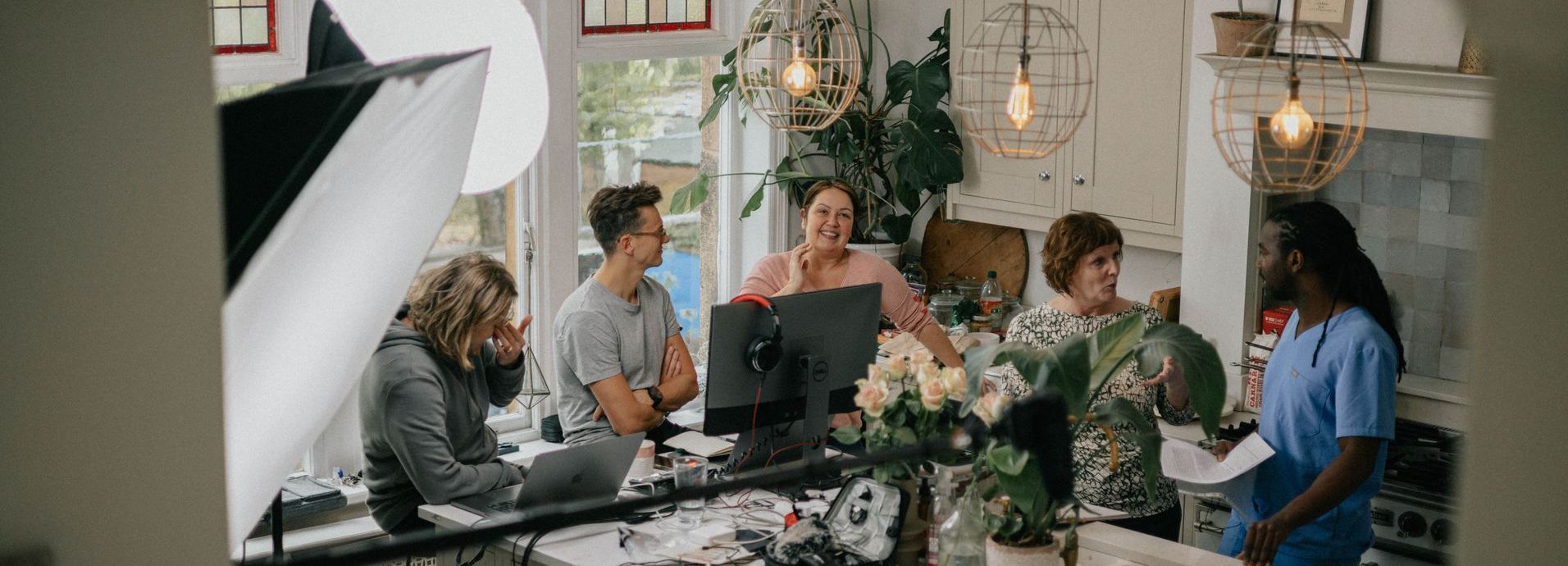 A group of people are sitting around a table with laptops.