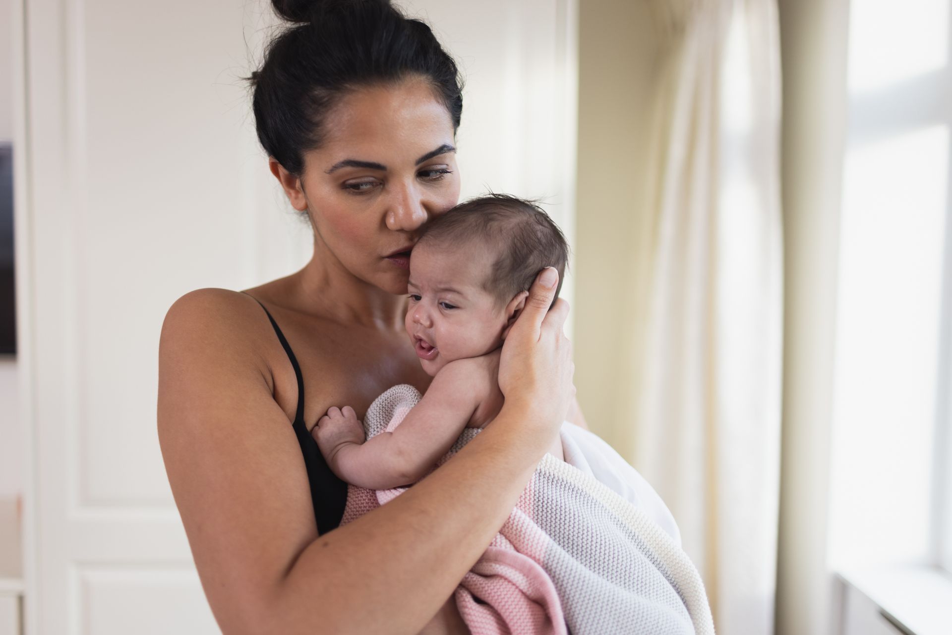 A woman is holding a baby wrapped in a towel.