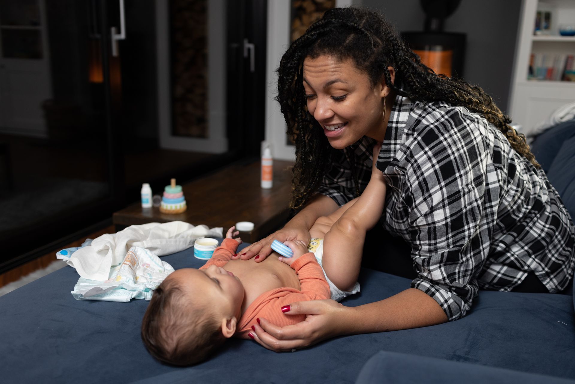 A woman is changing a baby 's diaper on a couch.