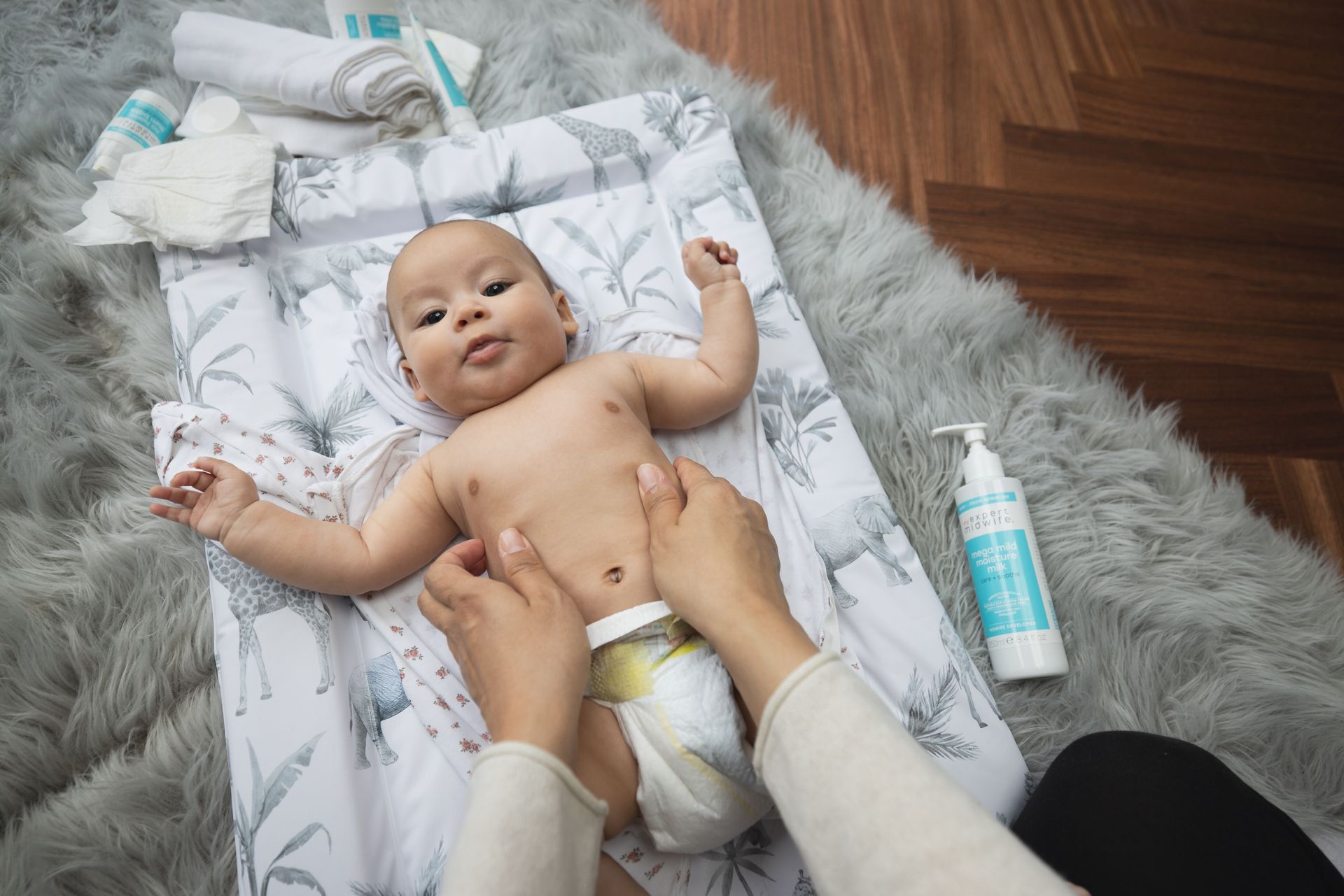 A woman is changing a baby 's diaper on a changing table.