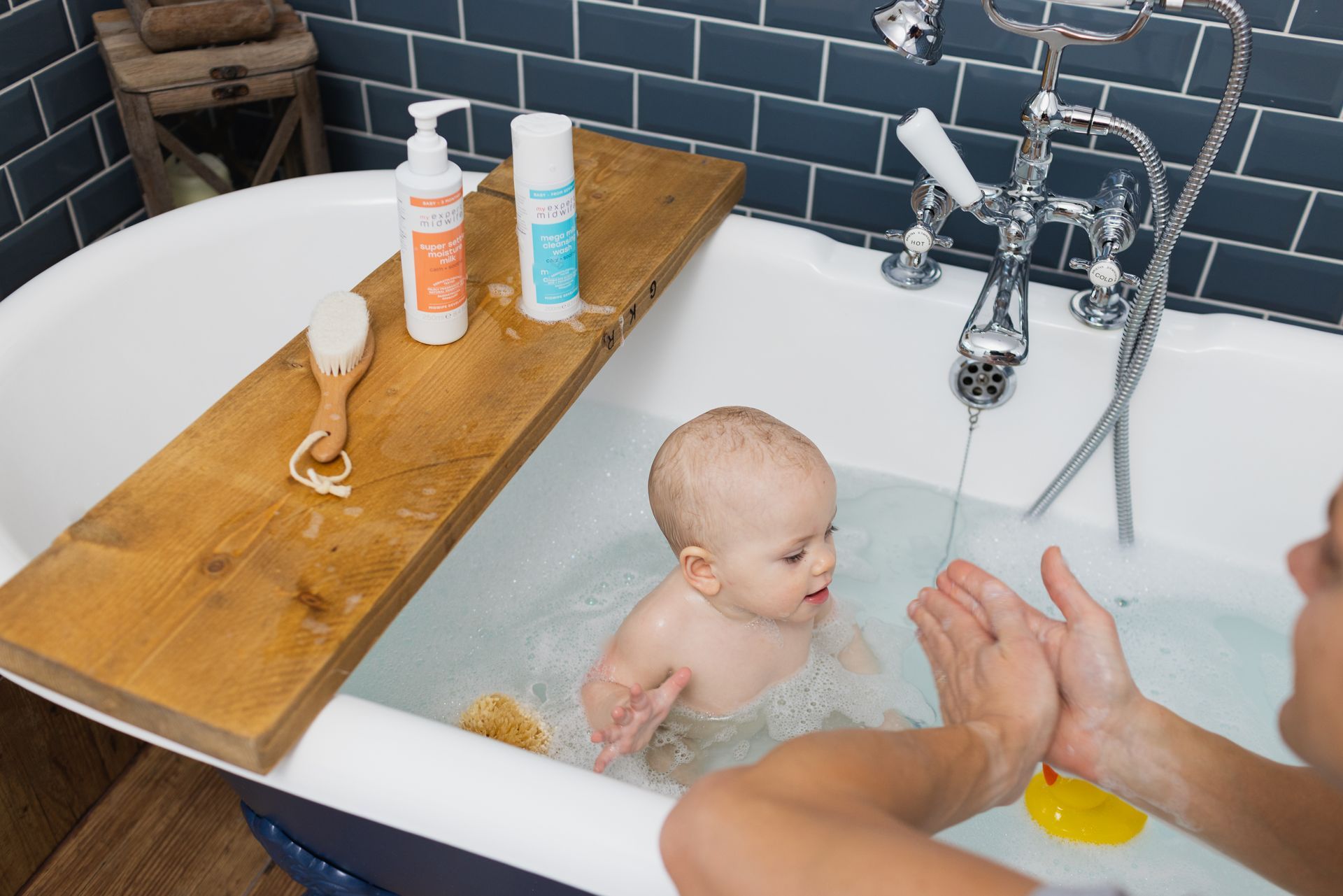 A woman is taking a bath with her baby in a bathtub.
