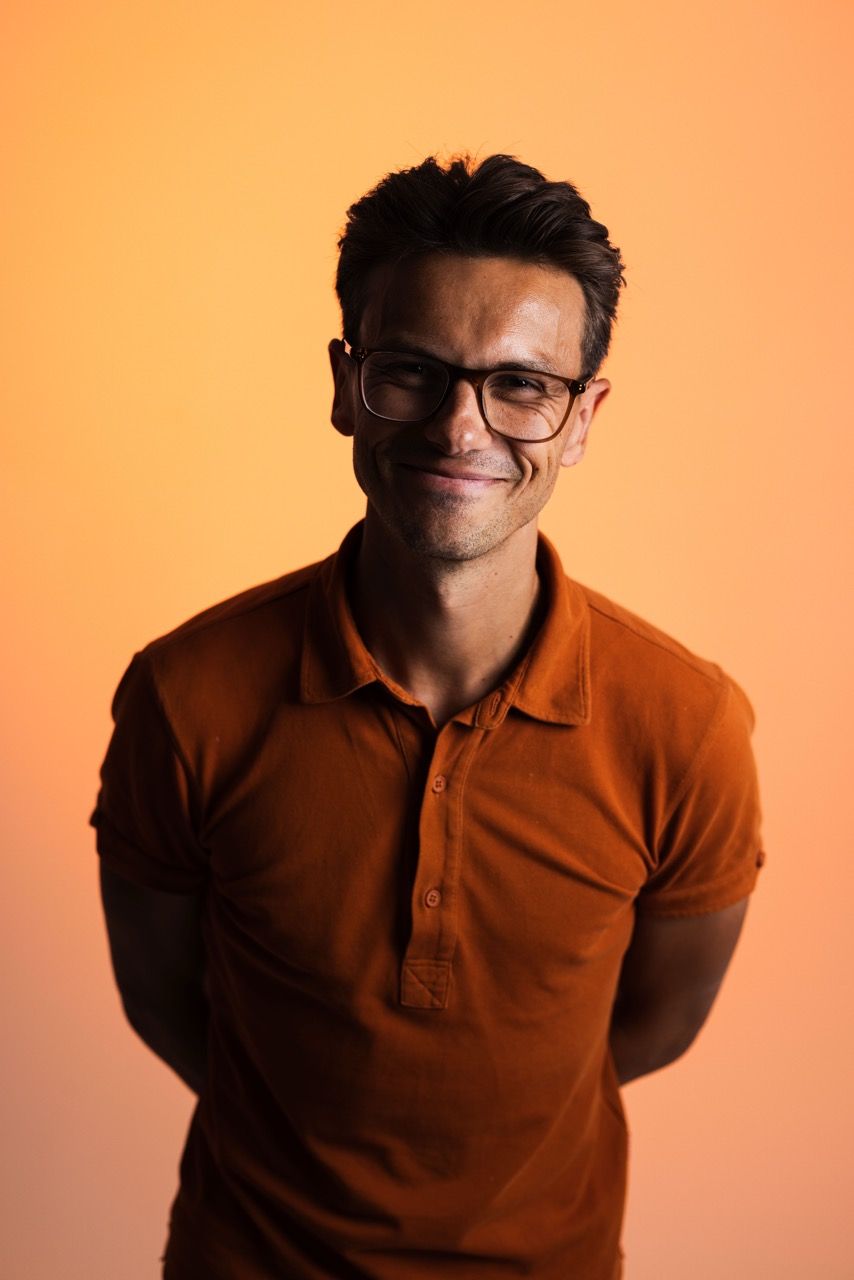 A man wearing glasses and a light blue shirt is smiling for the camera.