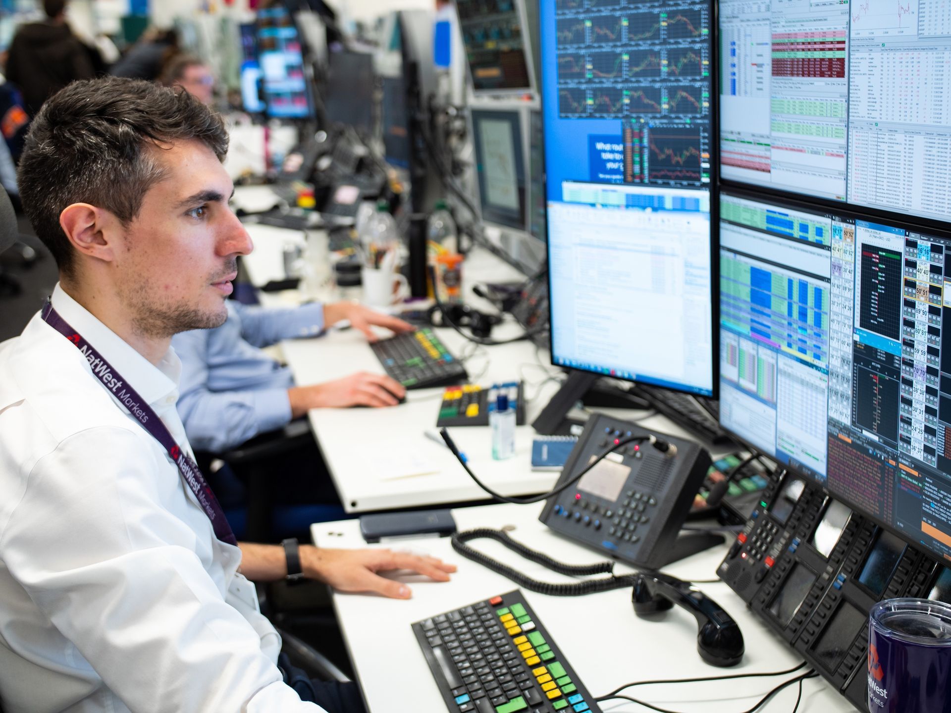 A man is sitting at a desk in front of a computer monitor.