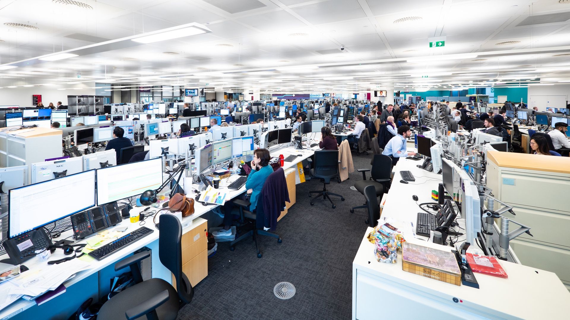 A large office with a lot of people working on computers.
