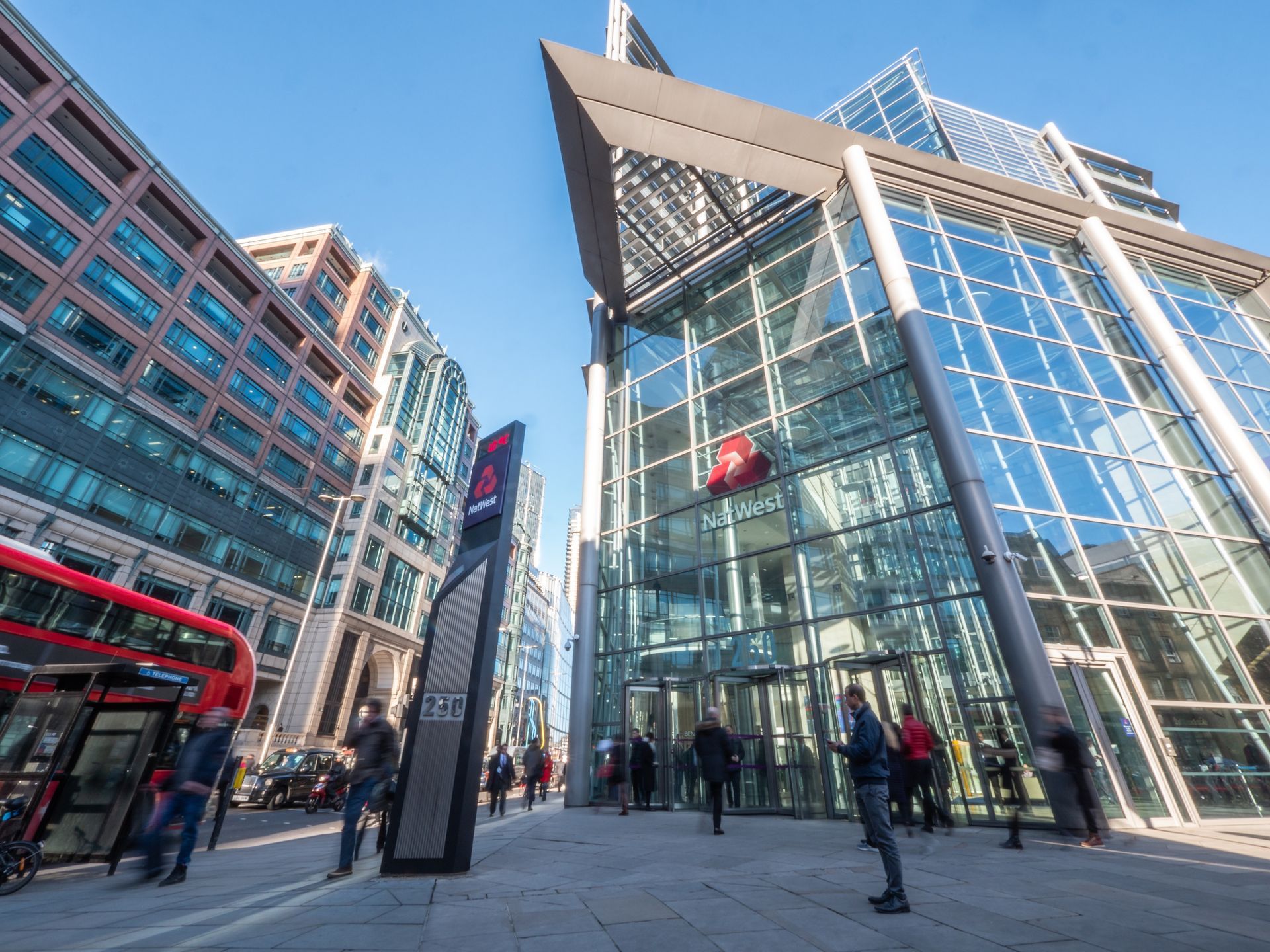 A group of people are walking in front of a large building.
