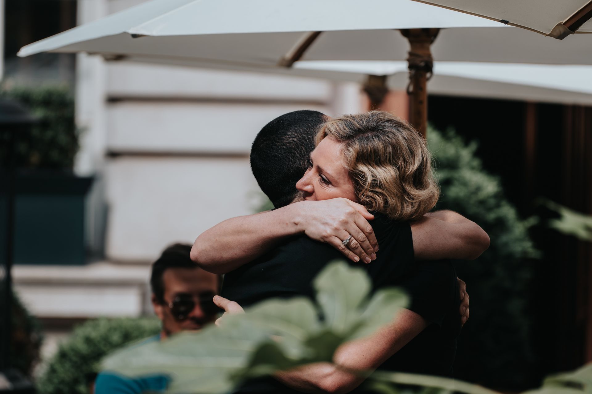 A man and a woman are hugging each other under an umbrella.