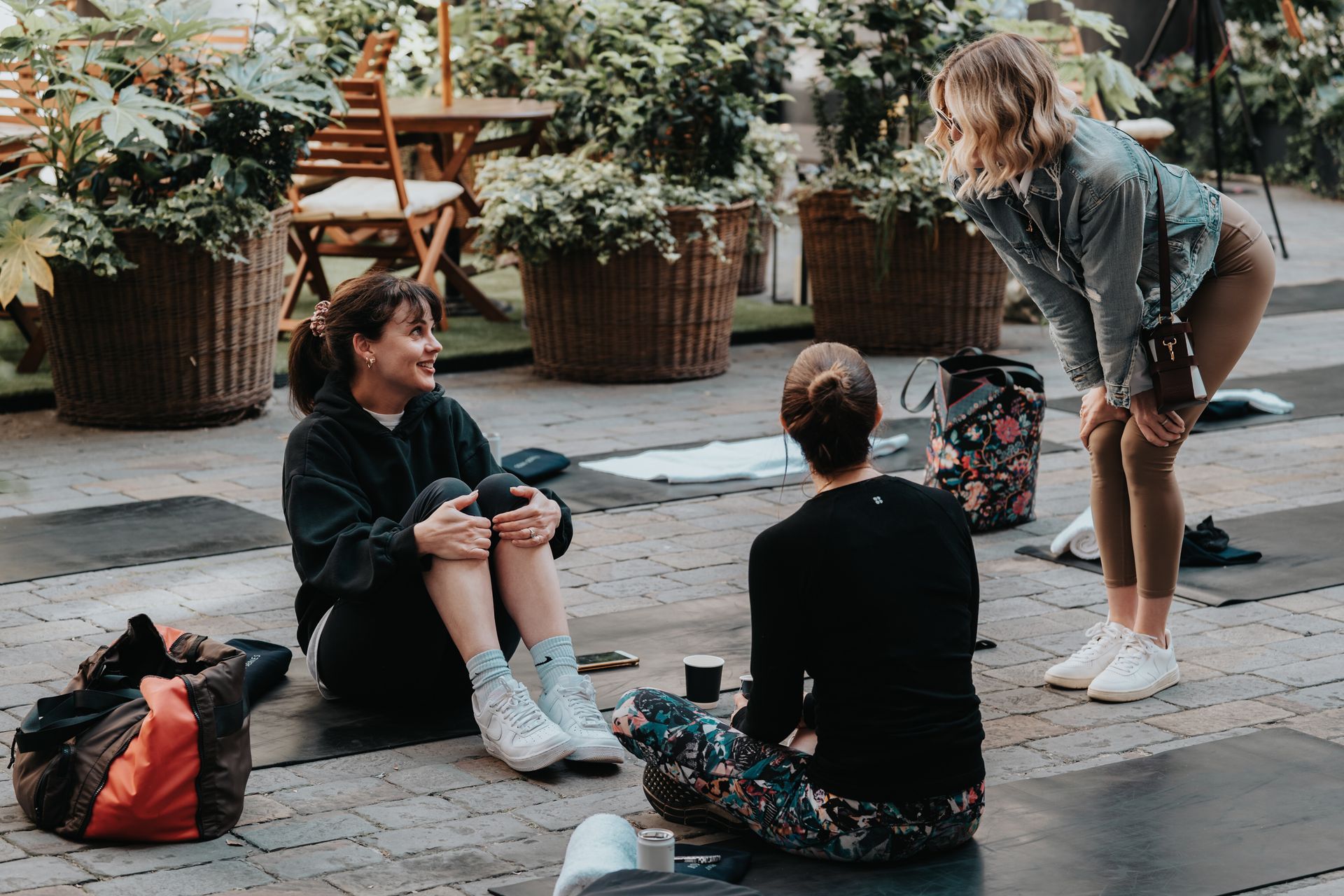 A group of women are sitting on a yoga mat on the ground.