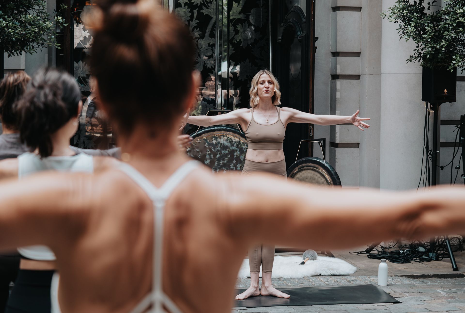 A group of women are doing yoga outside on a mat.