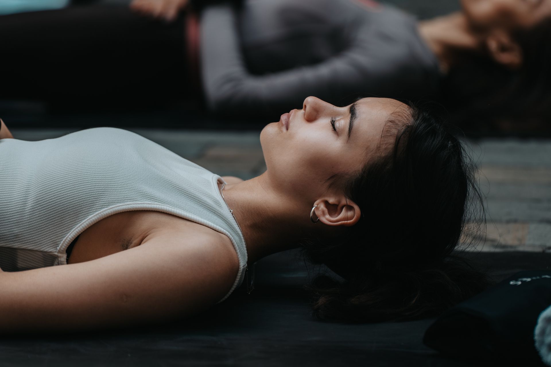 A woman is laying on her stomach on a yoga mat with her eyes closed.