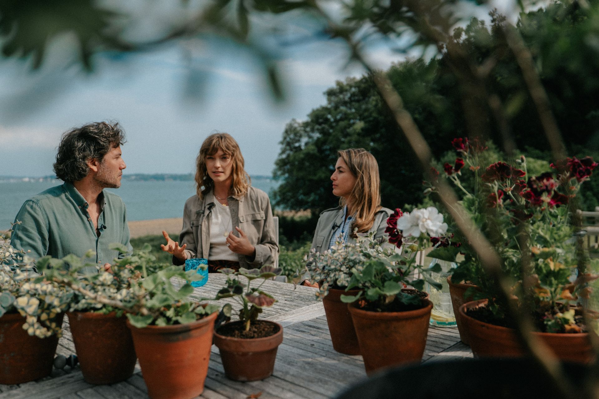 A group of people are sitting around a table with potted plants.