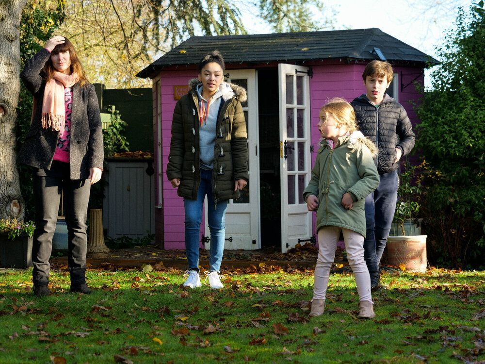 A group of people standing in front of a pink shed.