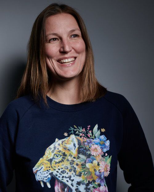 a woman is wearing a blue sweatshirt with a leopard and flowers on it .