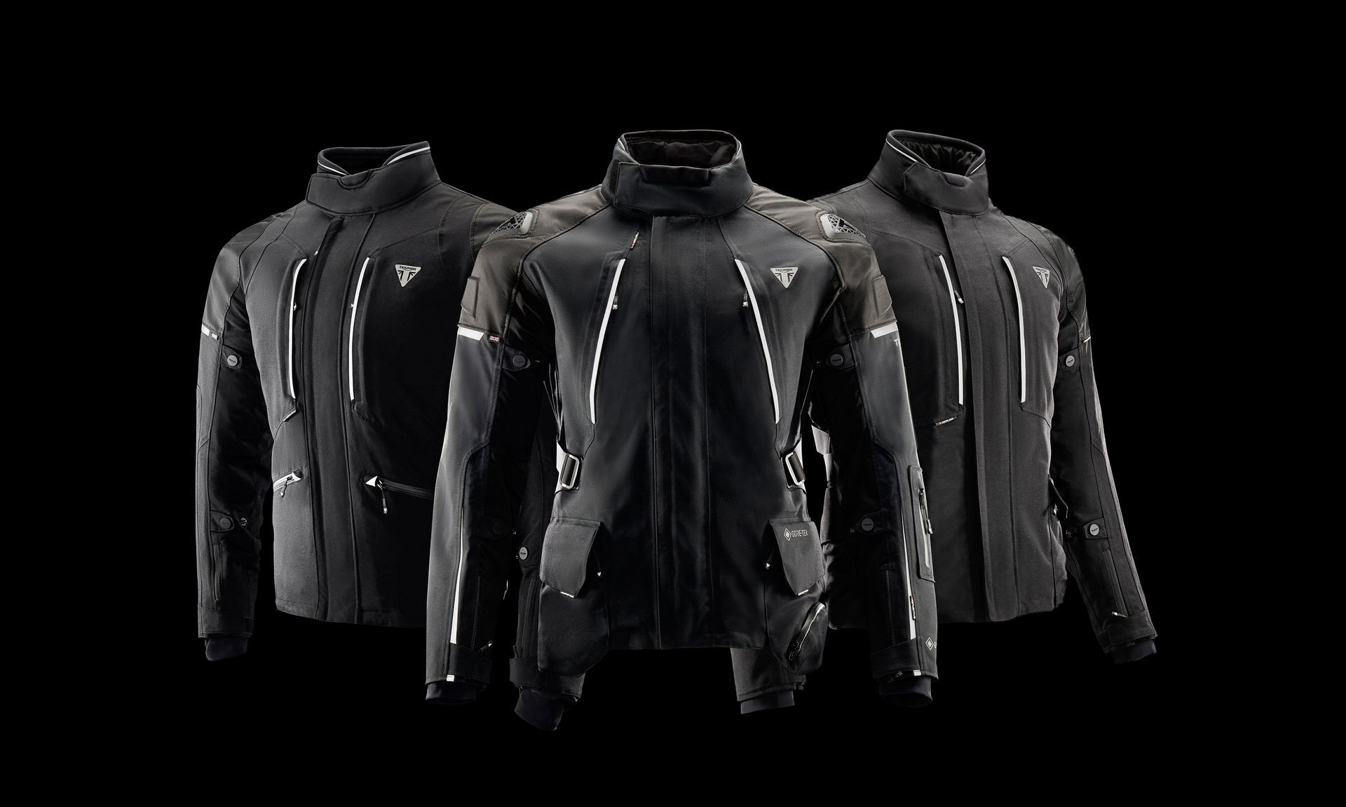 Three black jackets are sitting next to each other on a black background.