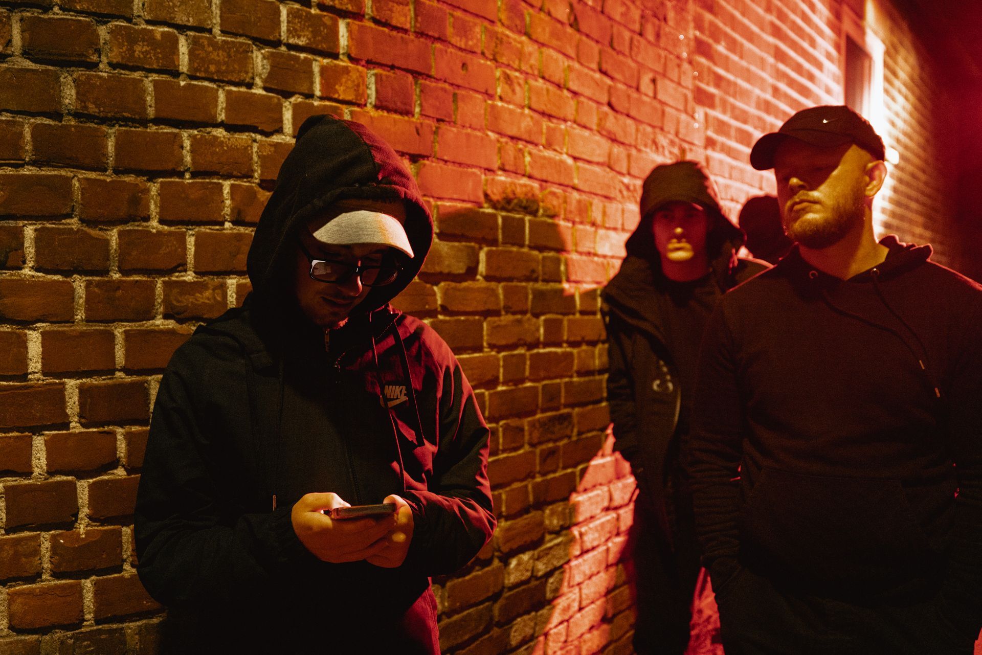 A group of men are standing next to a brick wall.