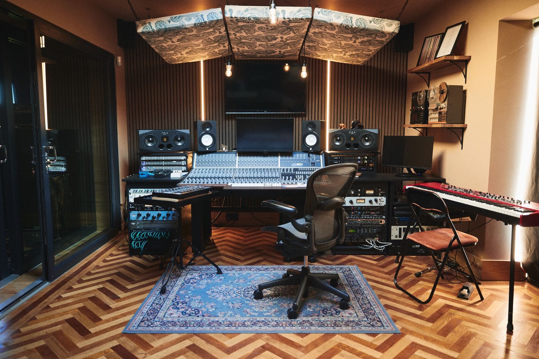 A recording studio with a wooden floor and a rug on the floor.