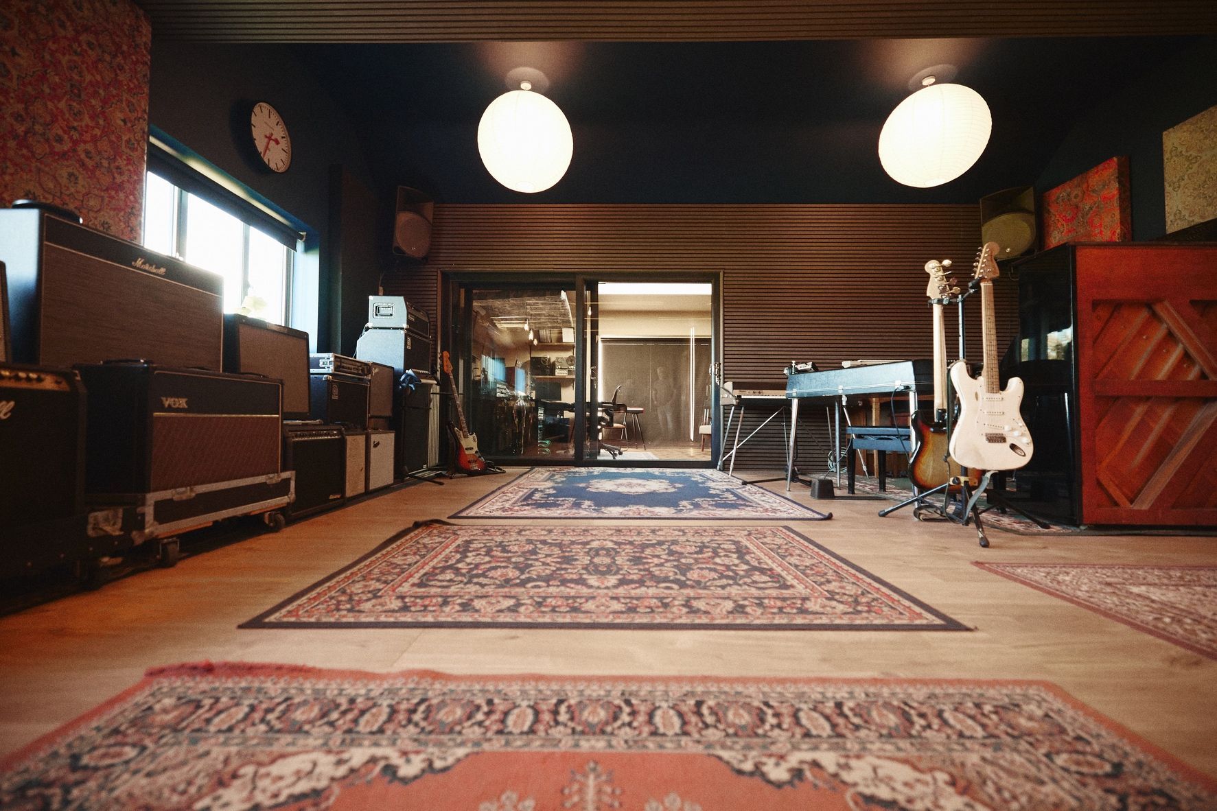 There are many guitars in the room and a rug on the floor.