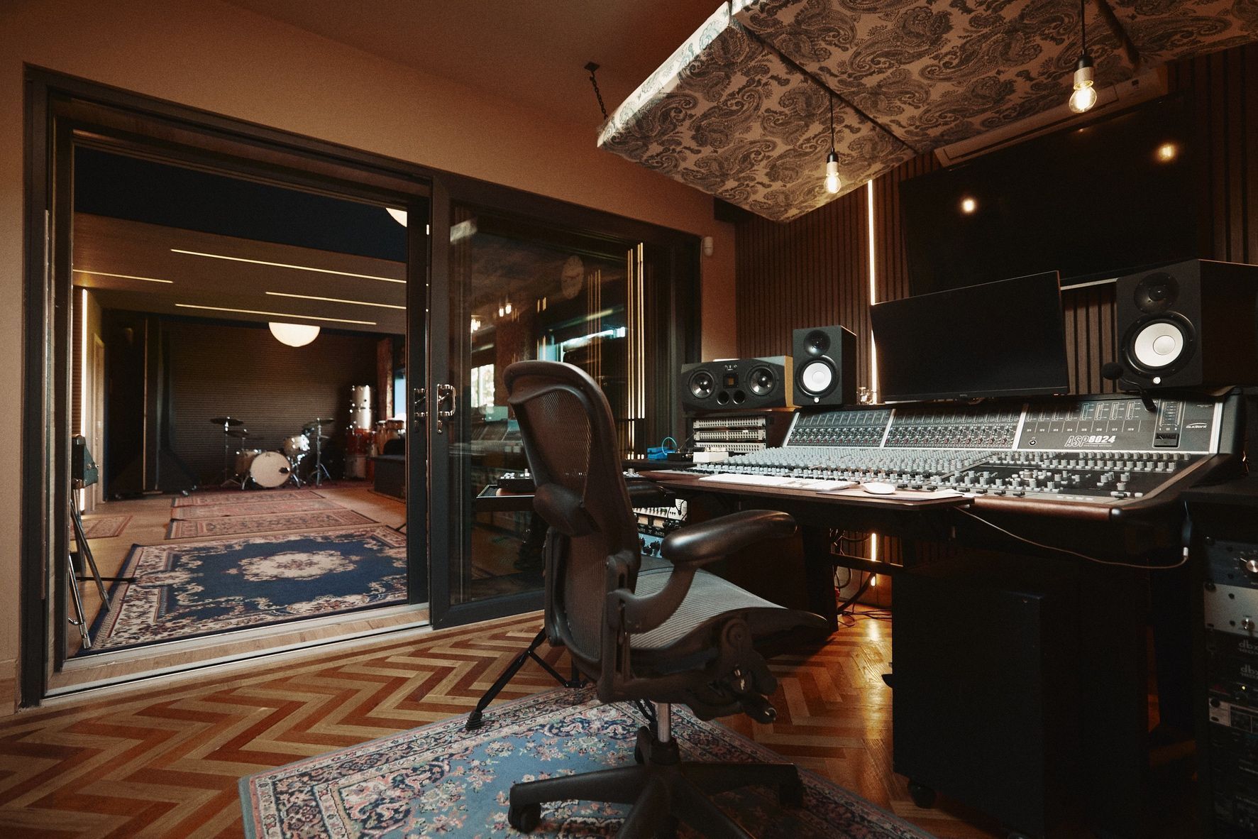 A recording studio with a keyboard , monitors , and a chair.