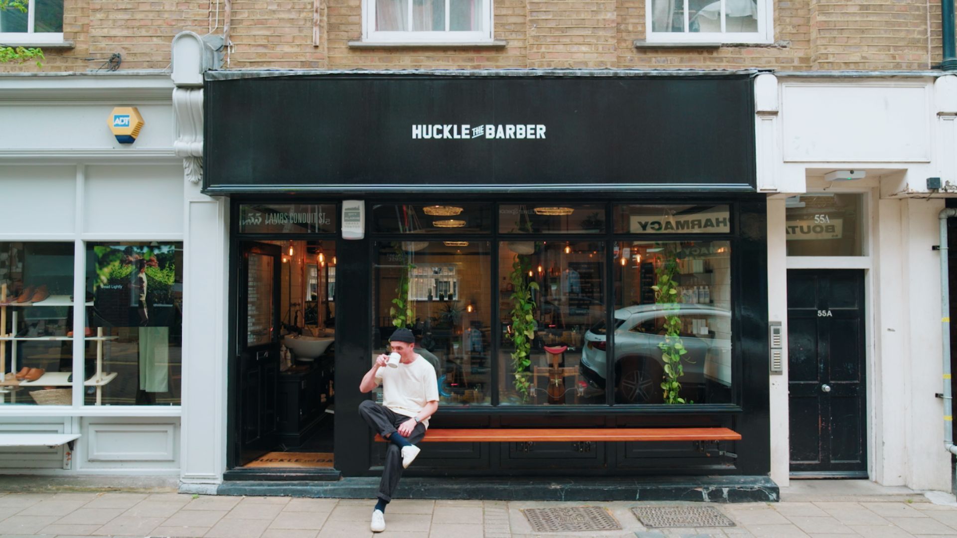 A man is sitting on a bench in front of a store.