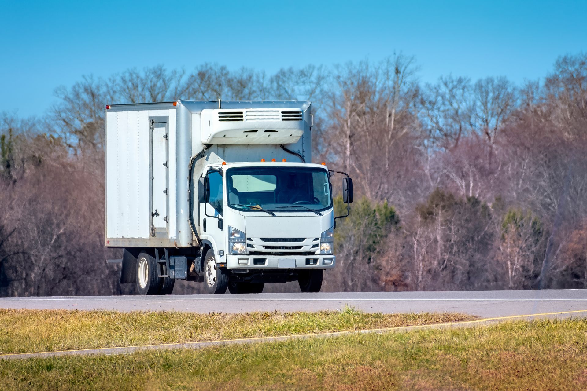 White refrigerated delivery truck transporting fresh produce. White refrigerated delivery truck transporting fresh produce.