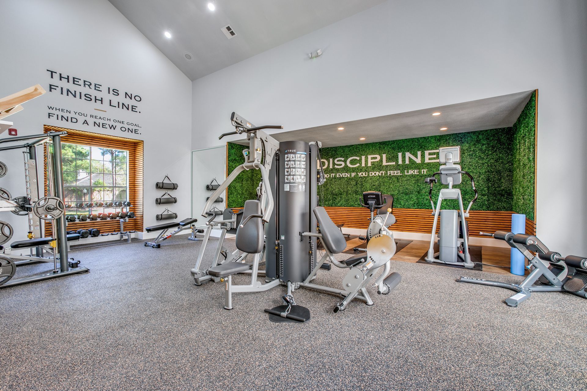 A gym with a lot of equipment and a wall with a quote on it at Marquis Champions Forest offers apartments in Klein ISD, Houston, TX.