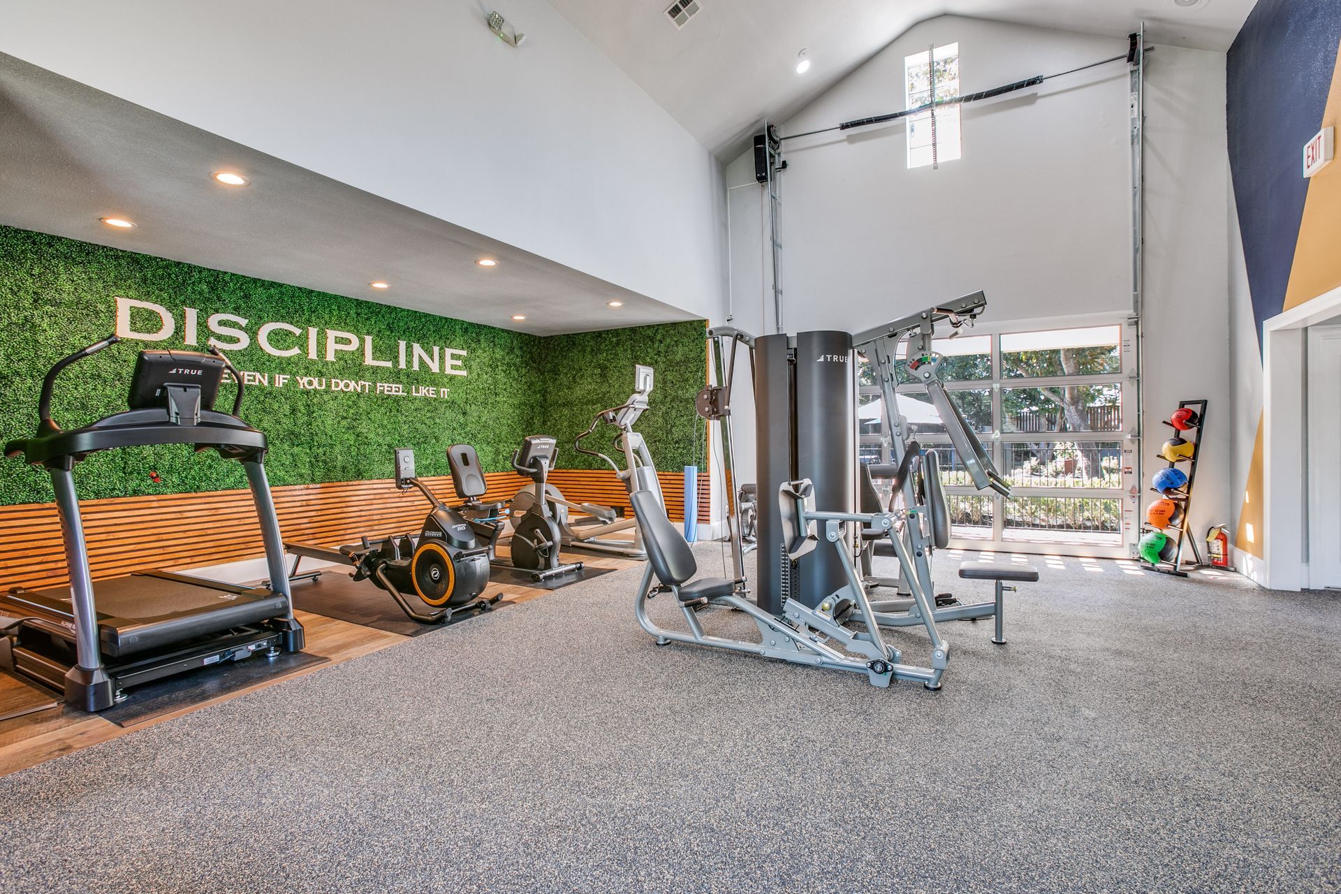 A gym with a lot of exercise equipment and a wall that says discipline at Marquis Champions Forest offers apartments for rent near Willowbrook Mall Houston, TX.