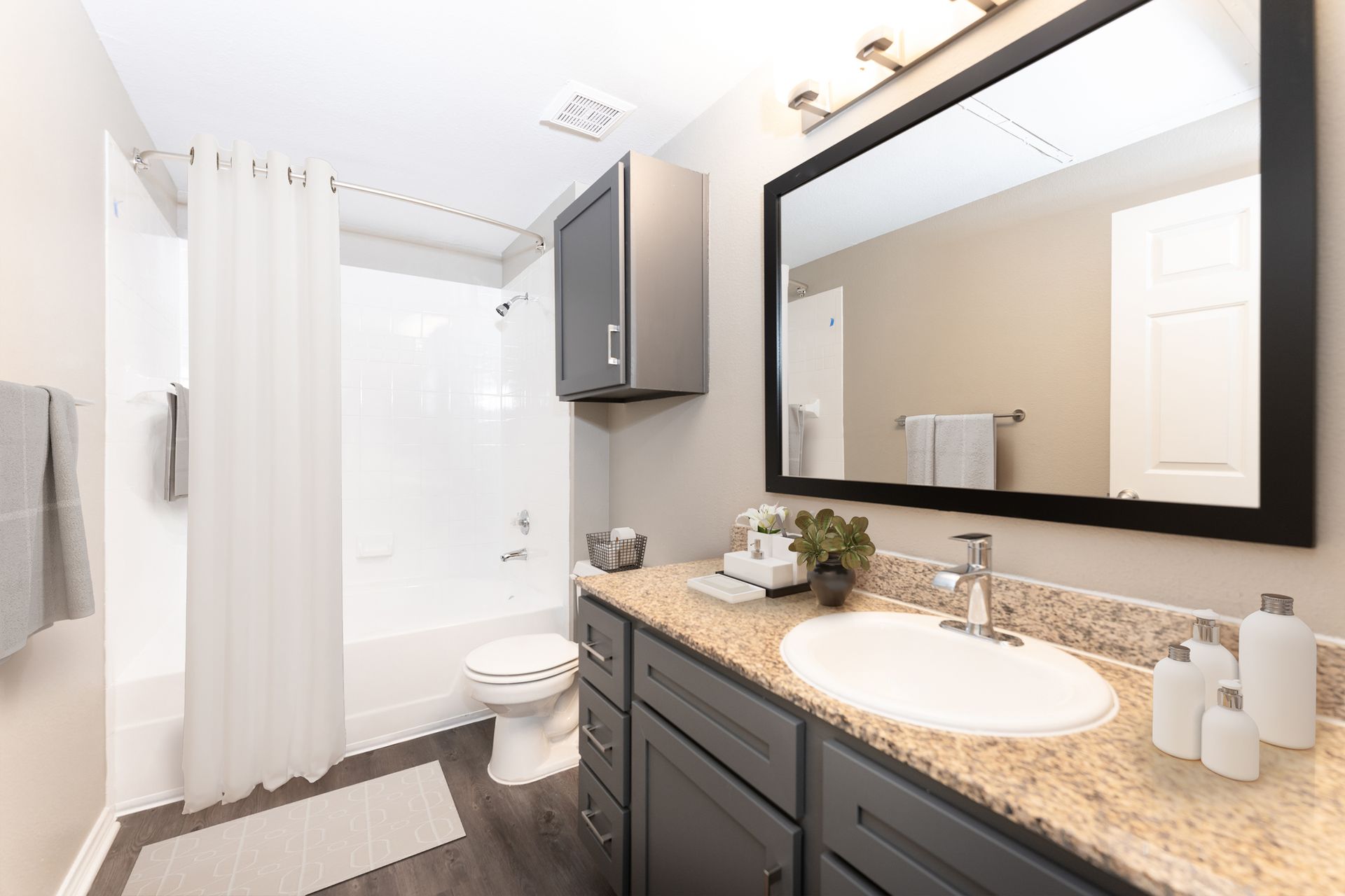 A bathroom with a sink, toilet, shower and mirror at Marquis Champions Forest offers apartments for rent in Northwest Houston, TX.