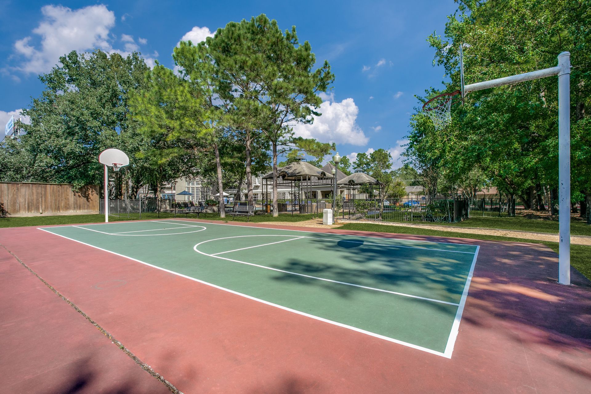 There is a basketball court surrounded by trees at Marquis Champions Forest offers apartments for rent with basketball court in Houston, TX.