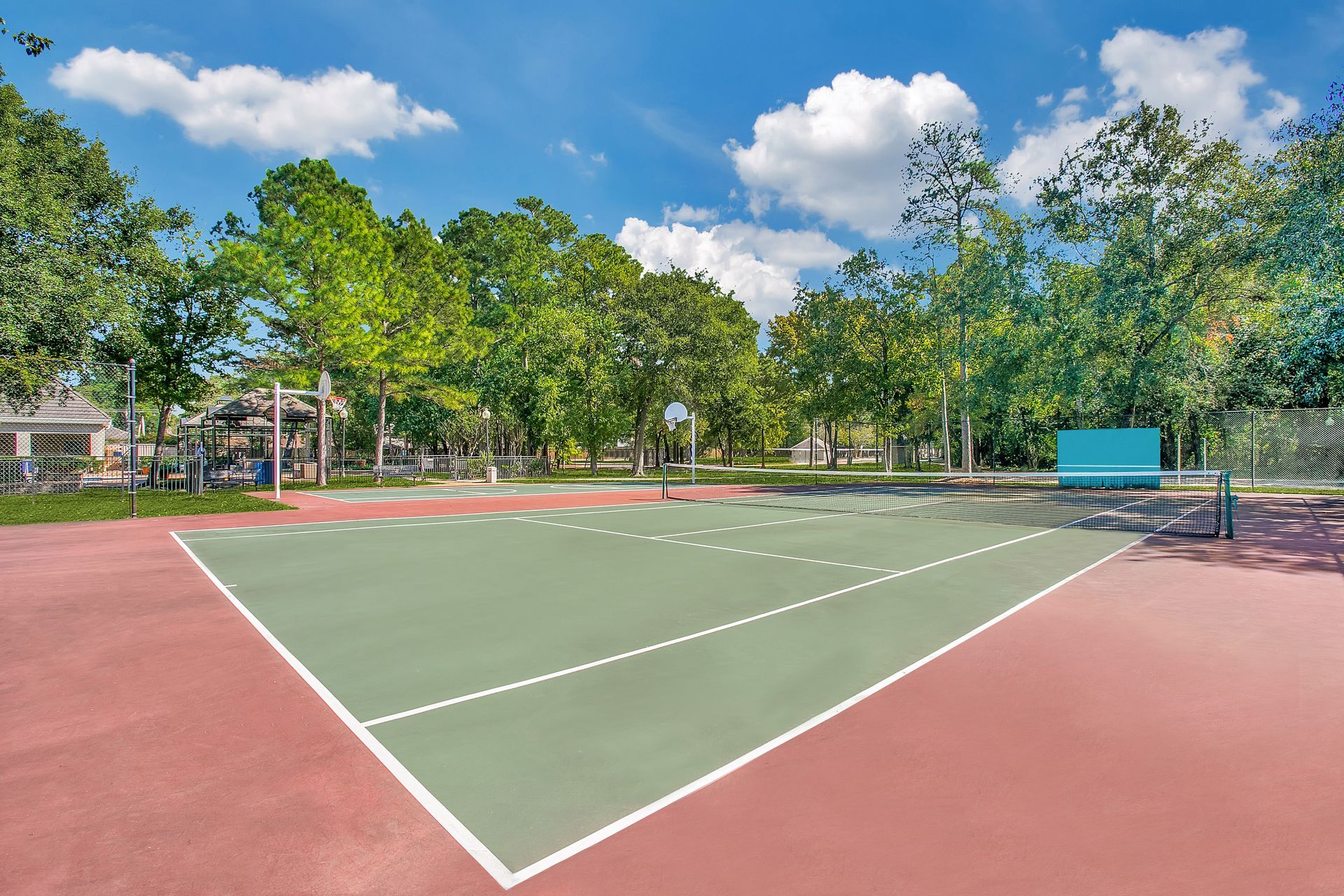 A tennis court in a park with trees in the background at Marquis Champions Forest offers apartments in Houston, TX.