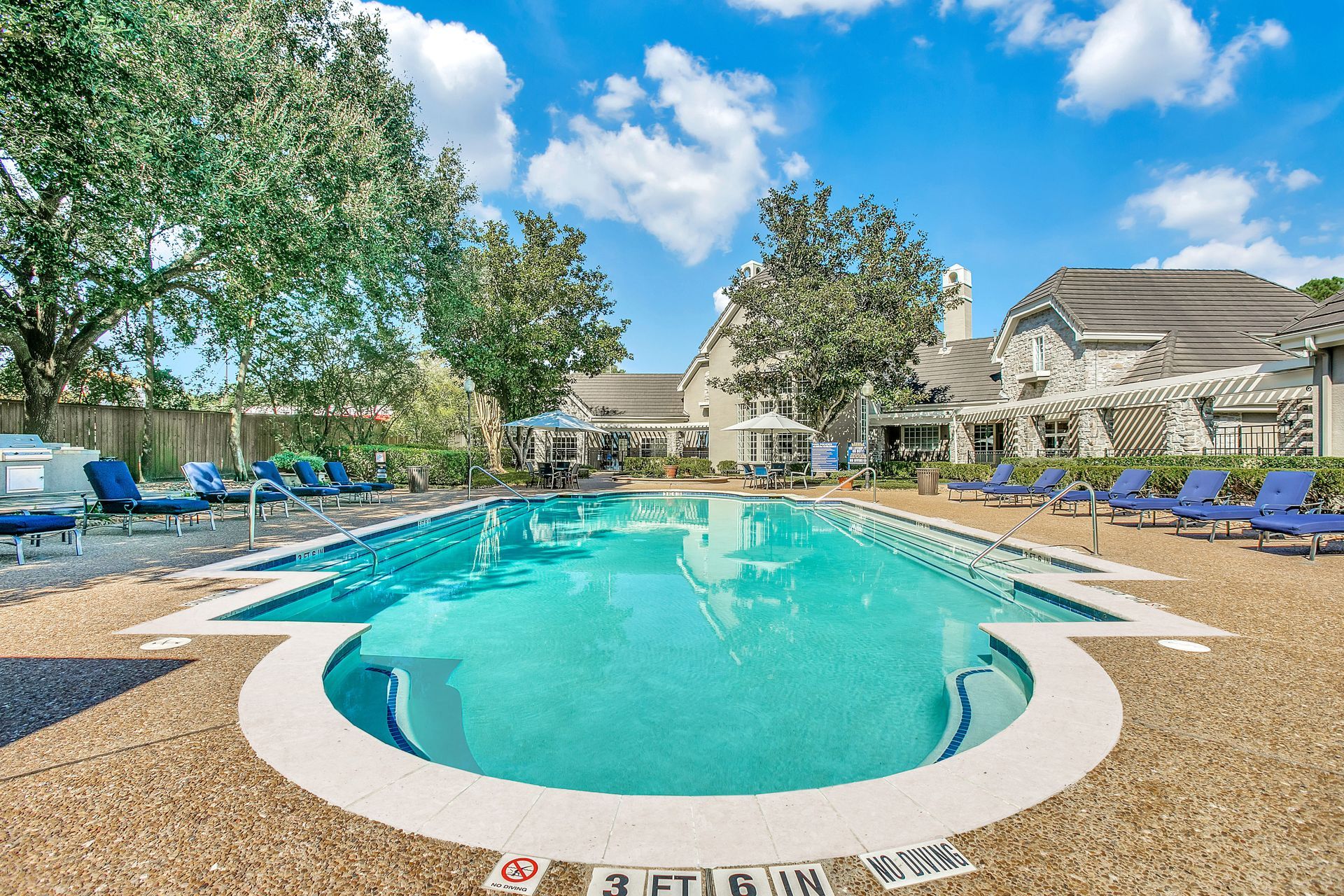 A large swimming pool is surrounded by chairs and trees at Marquis Champions Forest offers 1 and 2 bedroom apartments in Houston, TX.