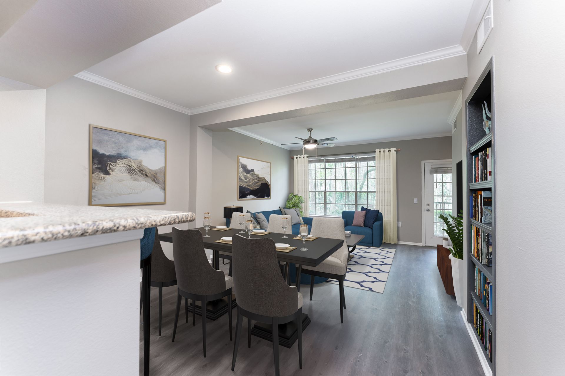 A living room with a dining table and chairs and a ceiling fan at Marquis Champions Forest offers apartments for rent in Houston, TX.