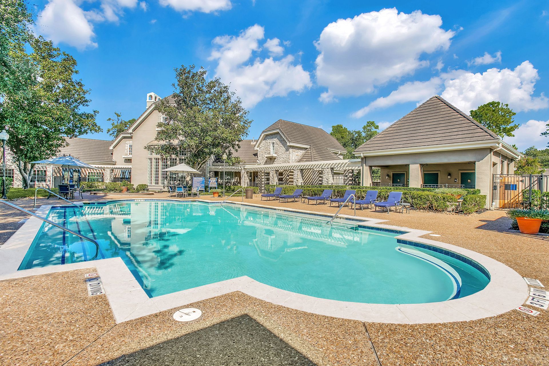 A large swimming pool with a apartment building in the background at Marquis Champions Forest offers apartments in Northwest Houston, TX.