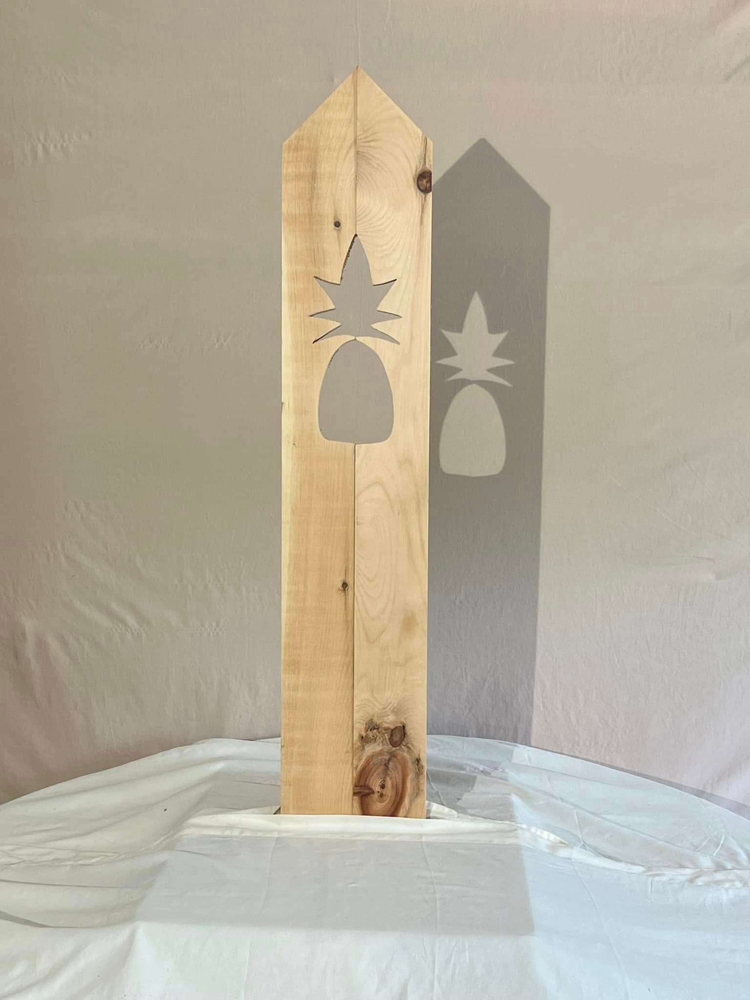 A wooden sculpture with a pineapple cut out of it is sitting on a table.