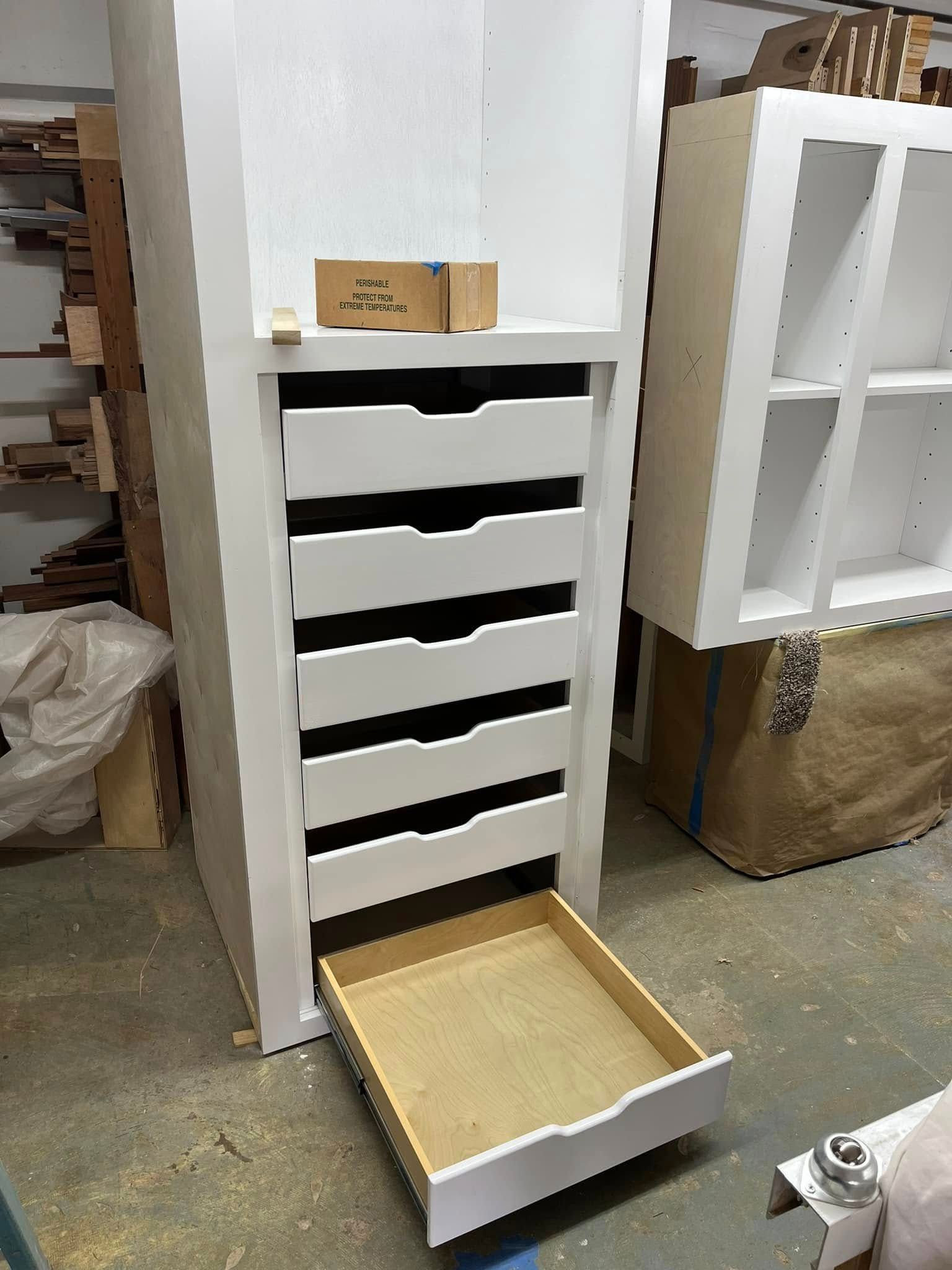 A white dresser with a drawer open in a room.
