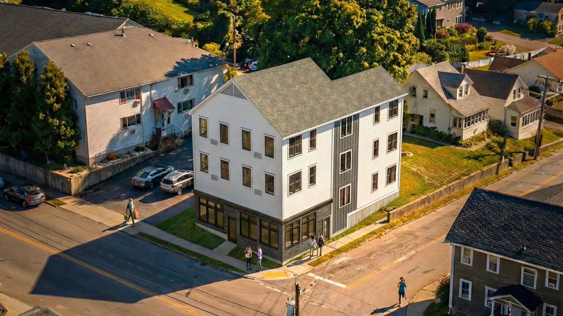 Tall white and slate colored, modern apartment building at corner of intersection
