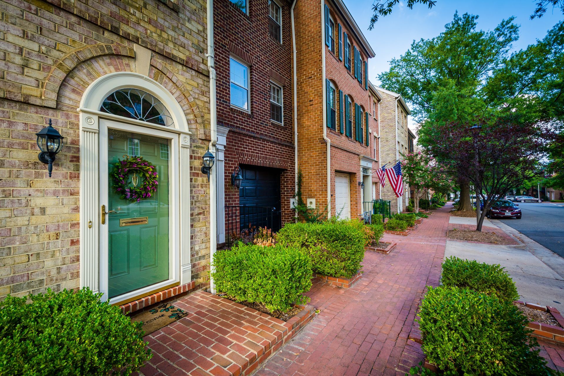 A brick building with a green door and a brick sidewalk in front of it.