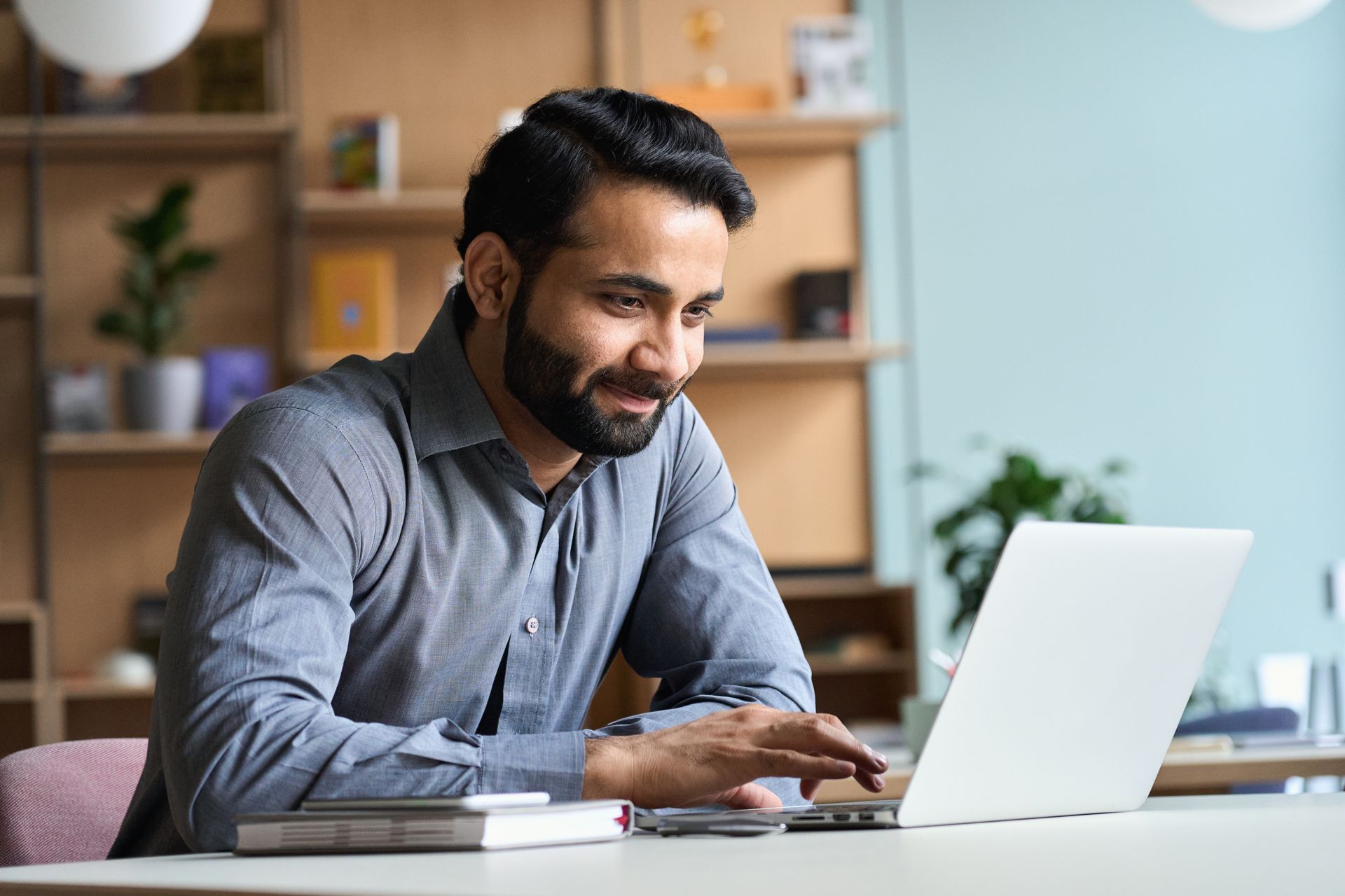 A man is sitting at a desk using a laptop computer.