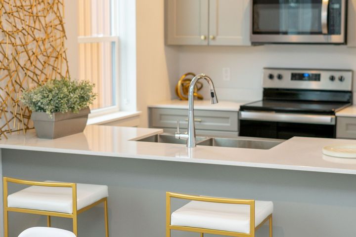 A kitchen with a sink , stove , microwave and two bar stools.