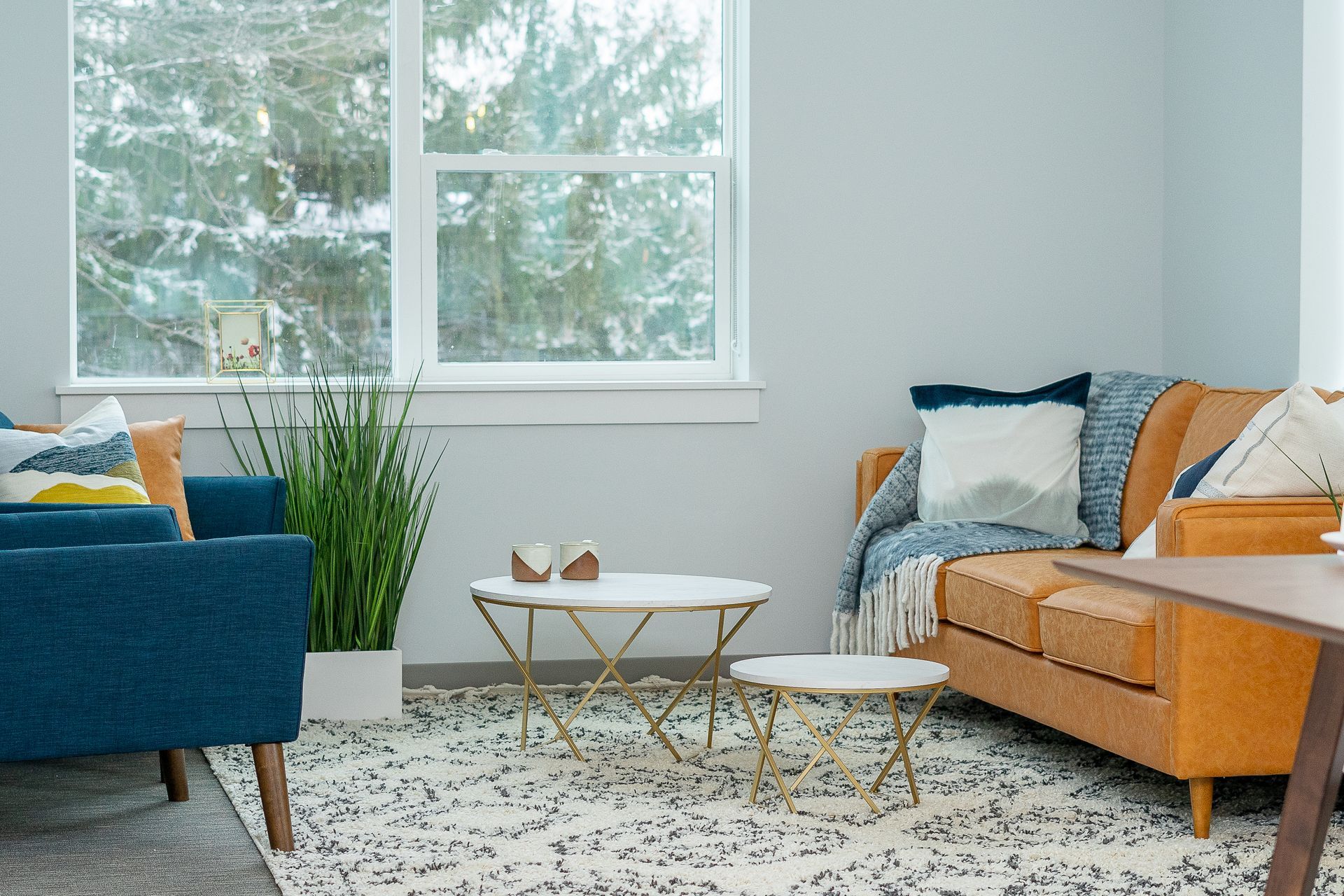 A living room with a couch , two chairs , a table and a window.