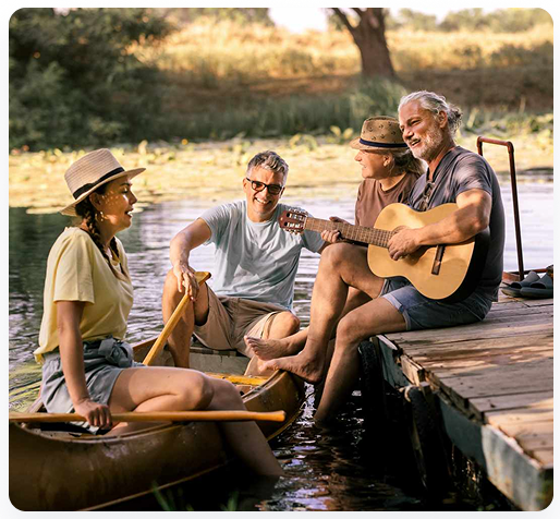 Friends relaxing on a wooden dock, playing guitar and chatting by the water in warm sunlight