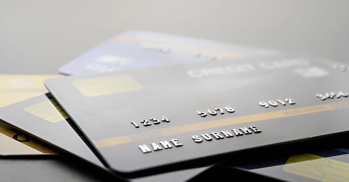 Stacked silver bank cards on a light background, with embossed numbers visible.