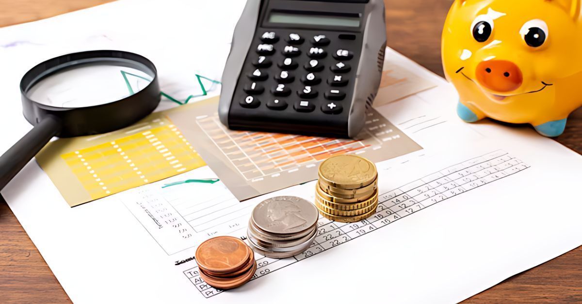 Calculator, magnifying glass, coins, and a yellow piggy bank on financial documents.