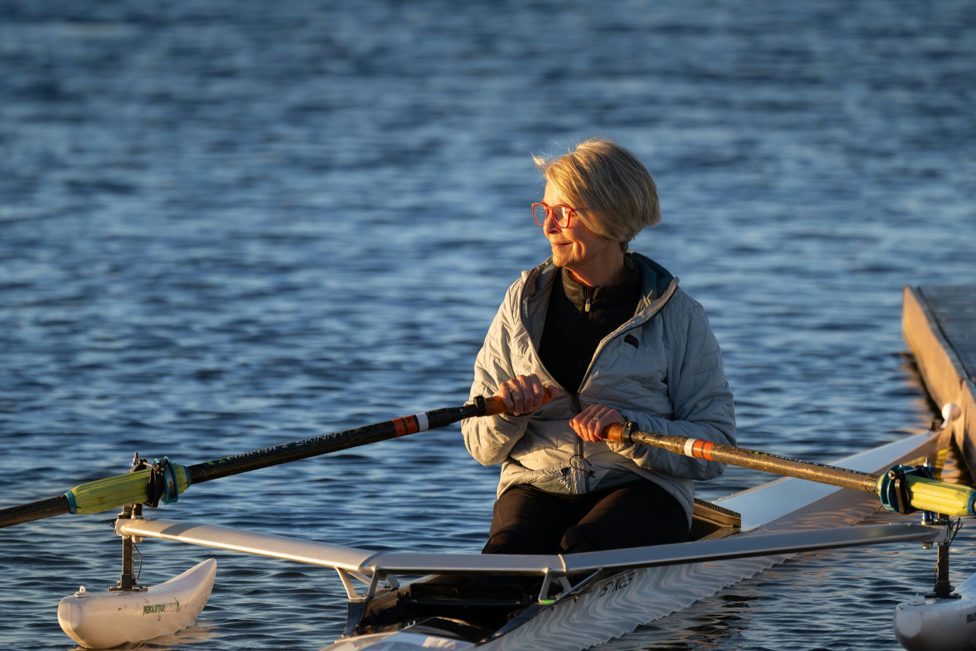 Person rowing a boat on calm water at sunset